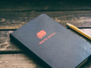 Book titled 'Write Ideas' sitting next to a pencil on a wooden table.